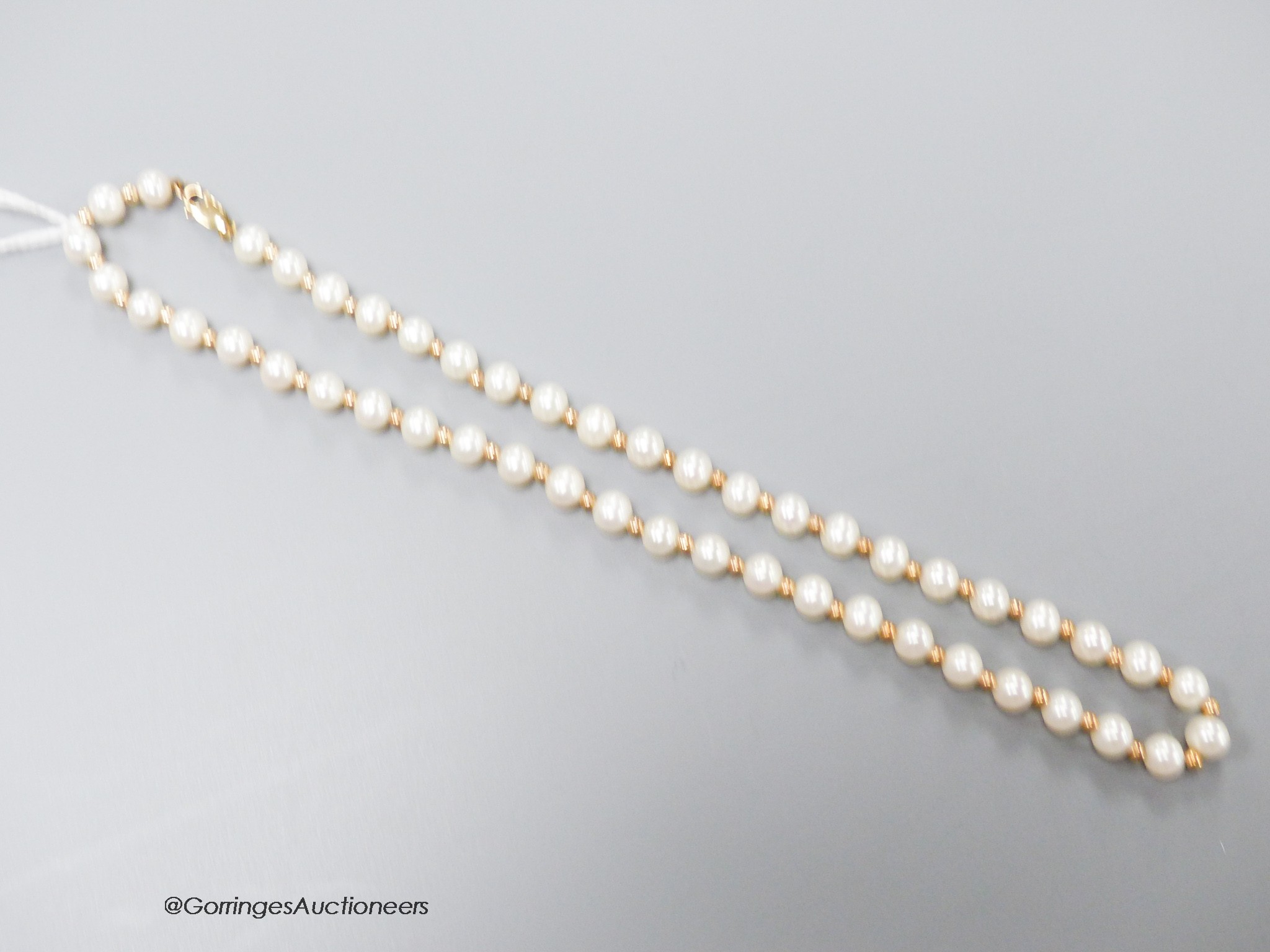 A modern single strand cultured pearl and yellow metal spacer set necklace, the clasp stamped 375, 39cm, gross weight 15.6 grams.